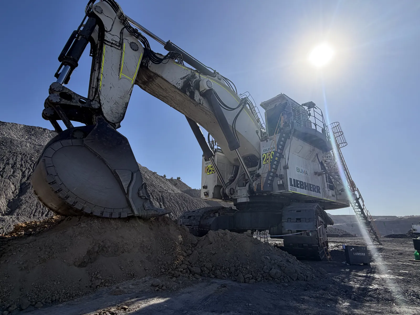 Liebherr excavator loading against the sun on a mine site