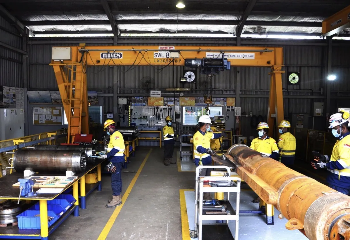 Workshop crew under a gantry crane during a component overhaul